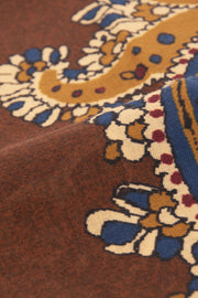 the detail of yellow and blue design on a brown wool scarf
