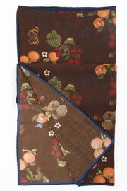 green leaves, tangerines, raspberries and white flowers on a brown wool scarf